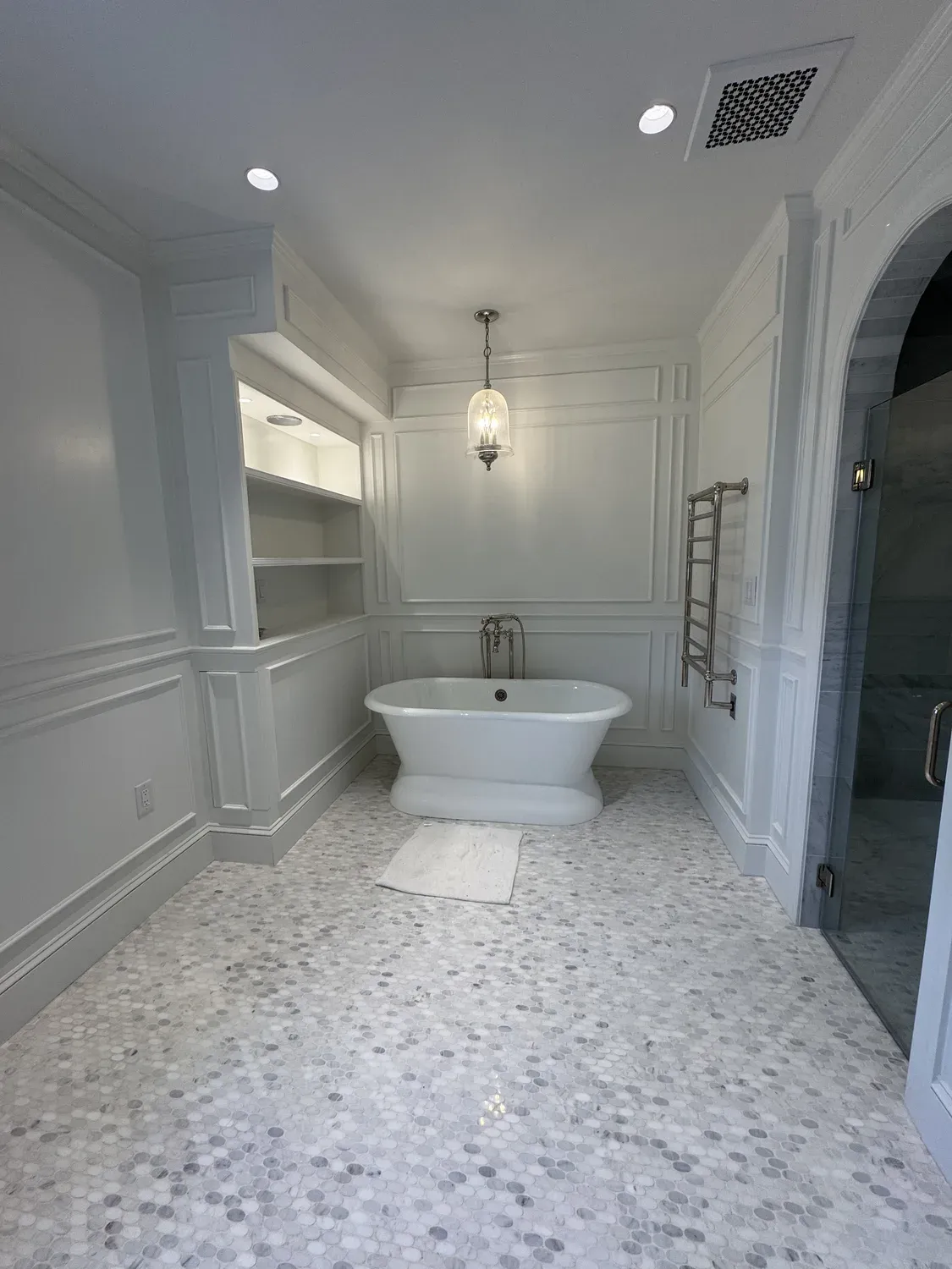 Bathroom remodel with freestanding tub and built-in shelving by Building America Construction